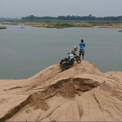 Motorcycle at the edge of a wide river landscape